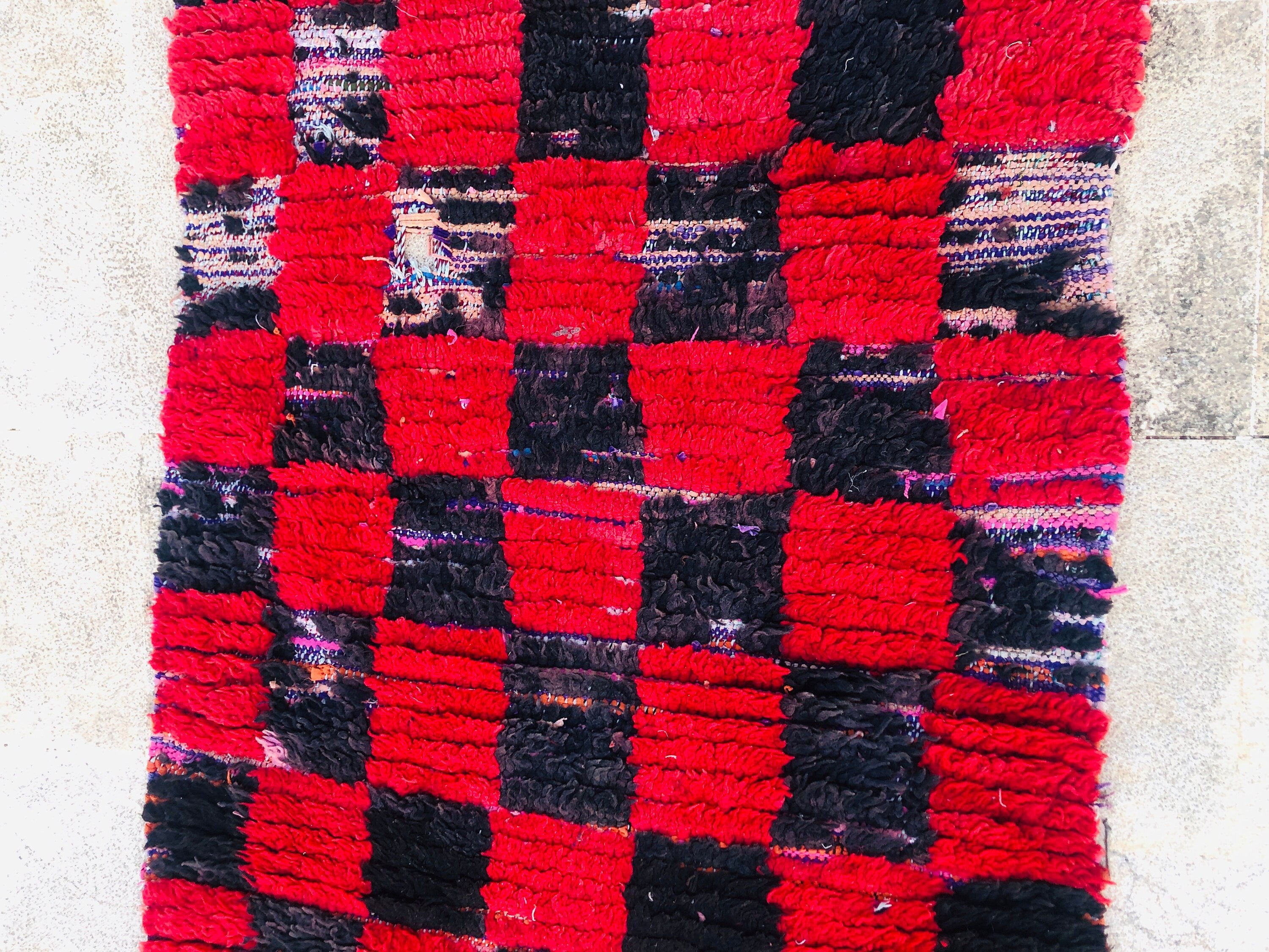 Handwoven red and black checkered rug, perfect for adding warmth to any space.