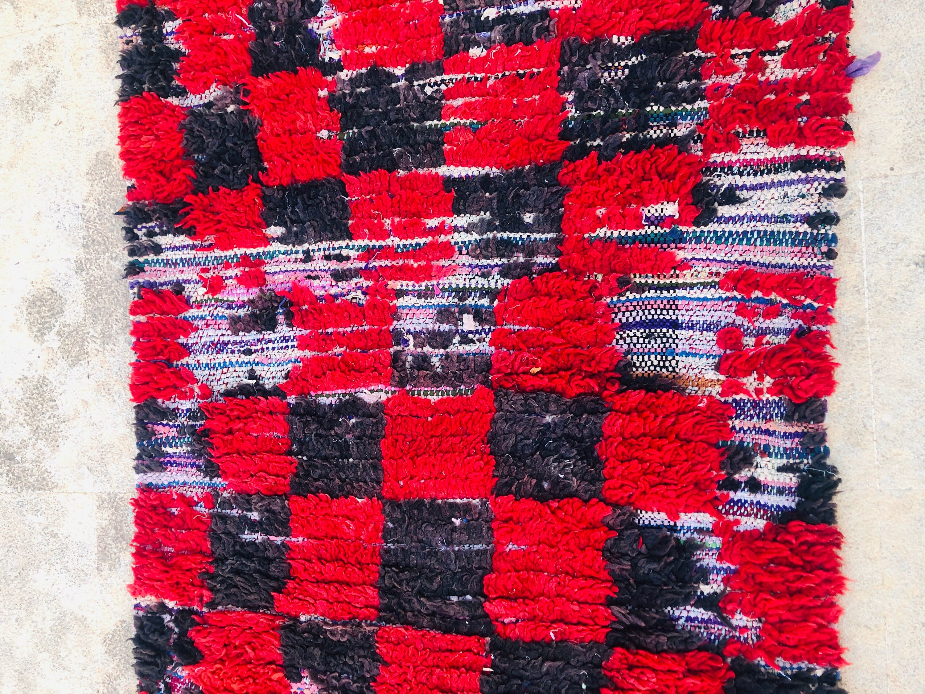 Red and black textured woven rug, perfect for adding warmth to any space.