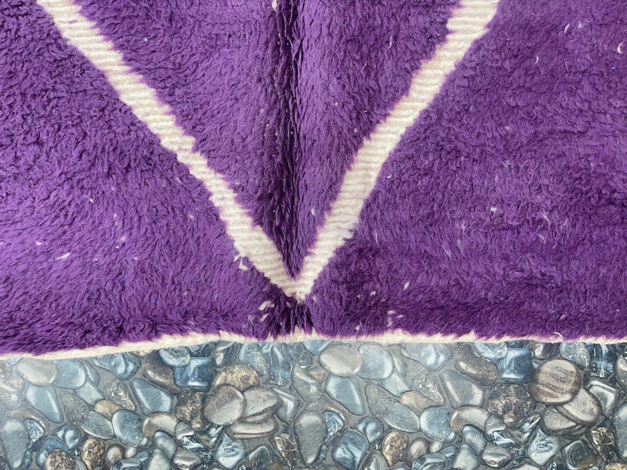 purple textured rug on smooth stone surface