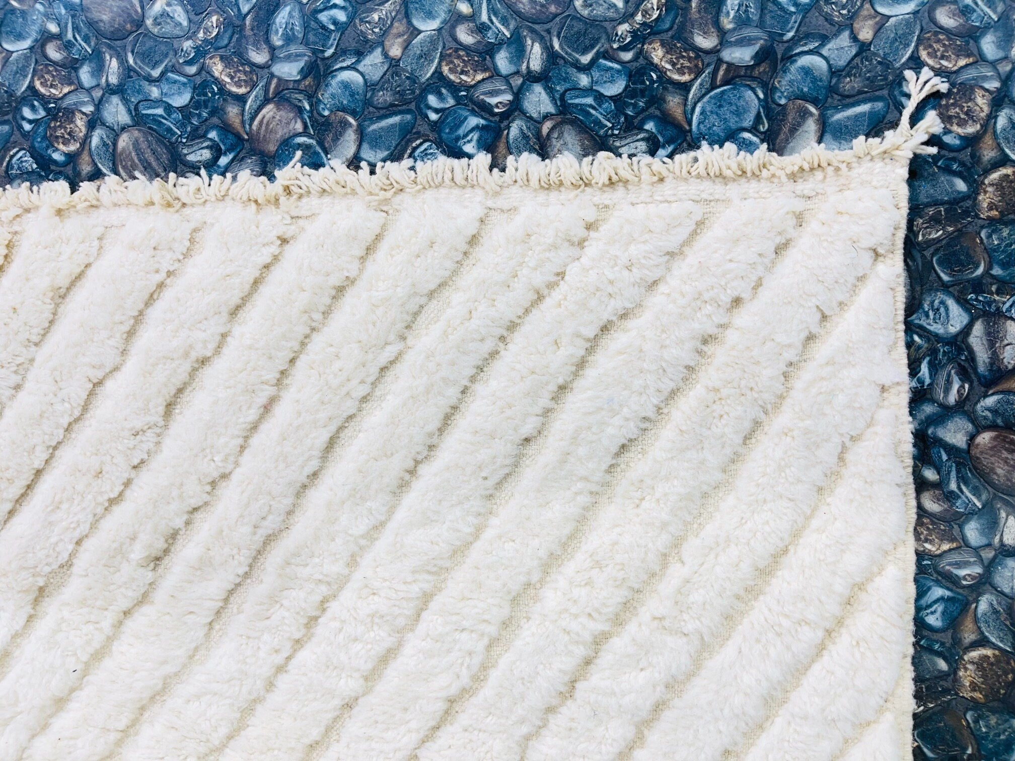 white textured rug on pebbled surface background