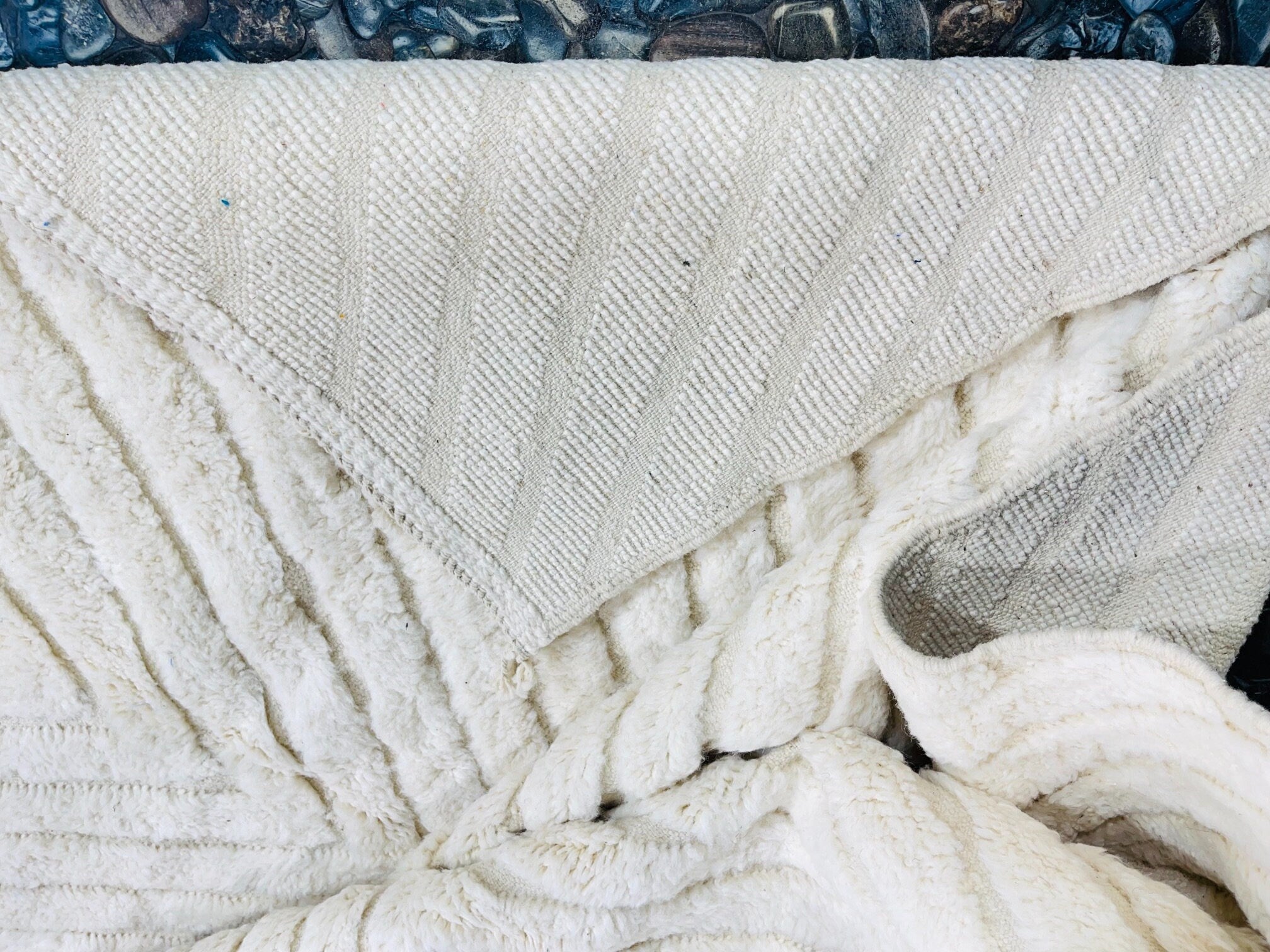 cozy textured white blanket on smooth stones