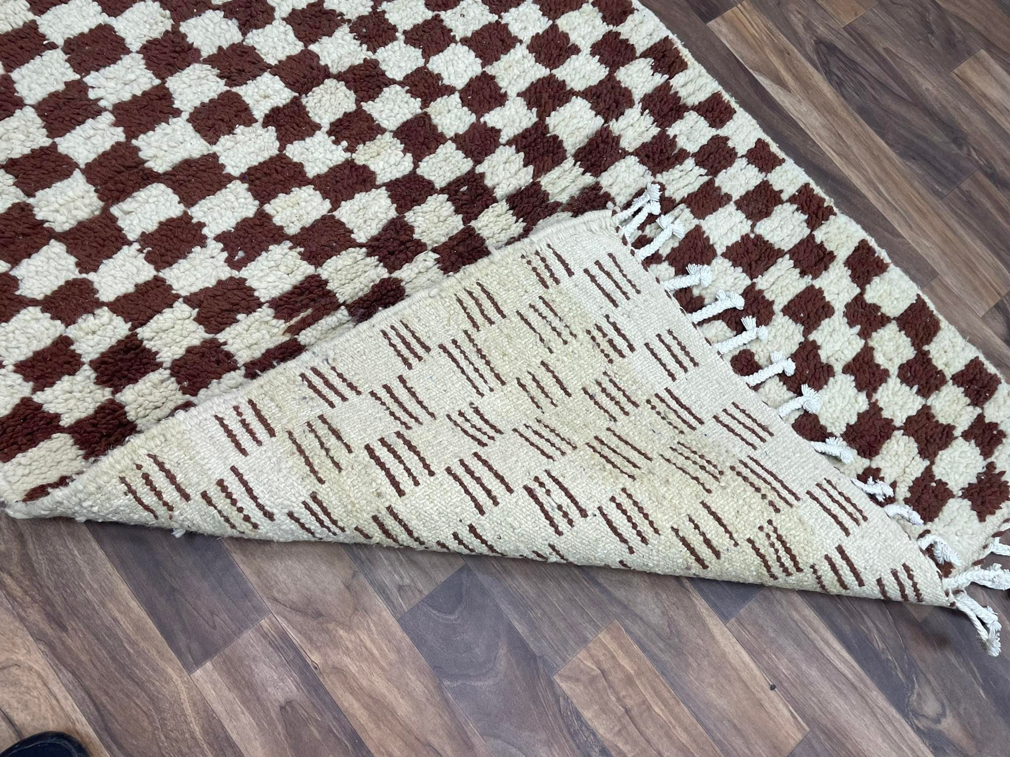 Brown and cream patterned area rug with fringed edges, showcasing reversible design and texture.