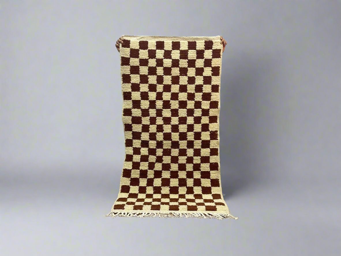 Checkered brown and cream woven rug with fringed edges for stylish home decor.