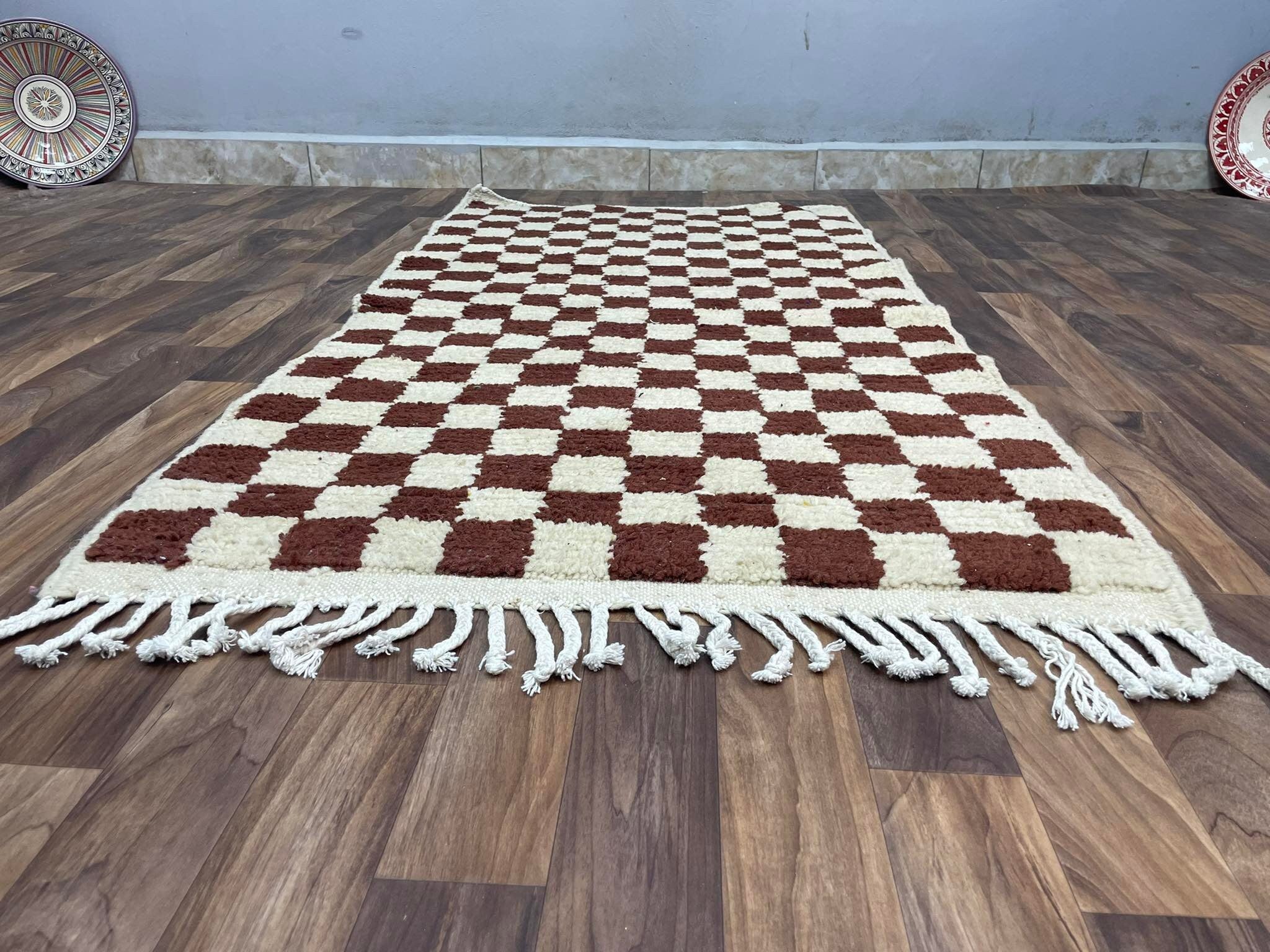 Checkered brown and cream area rug with fringes, perfect for home decor and comfort.