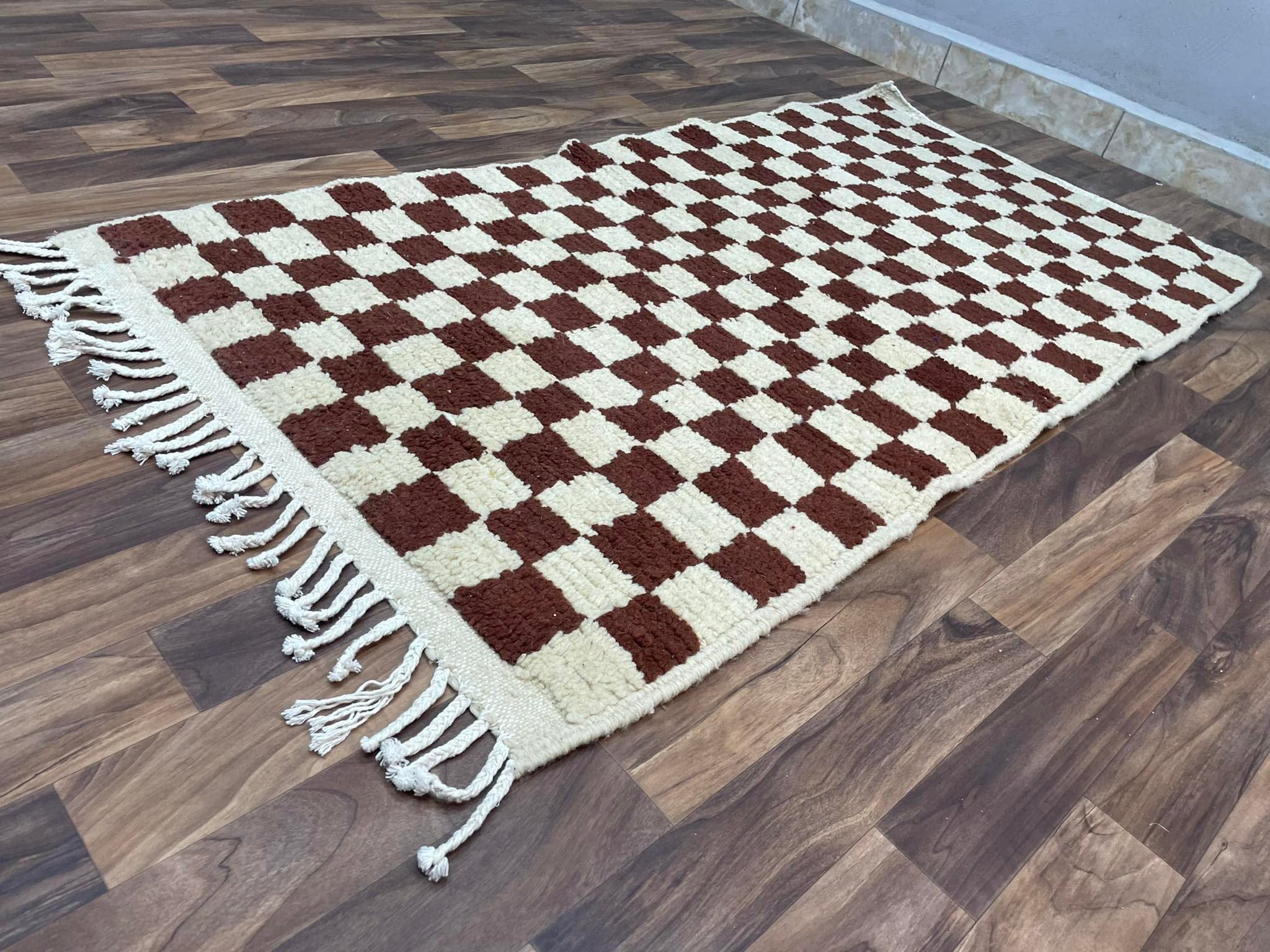 Checkered brown and cream area rug with fringes, perfect for home decor enhancement.