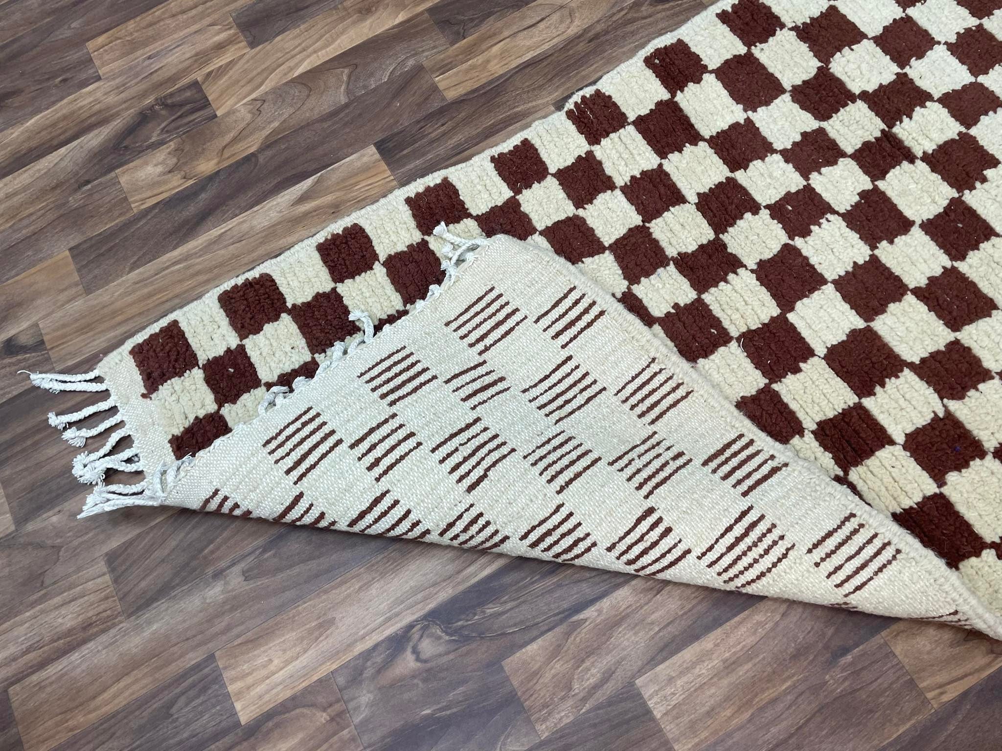 Handwoven checkered rug with fringes, ideal for home decor and comfort.