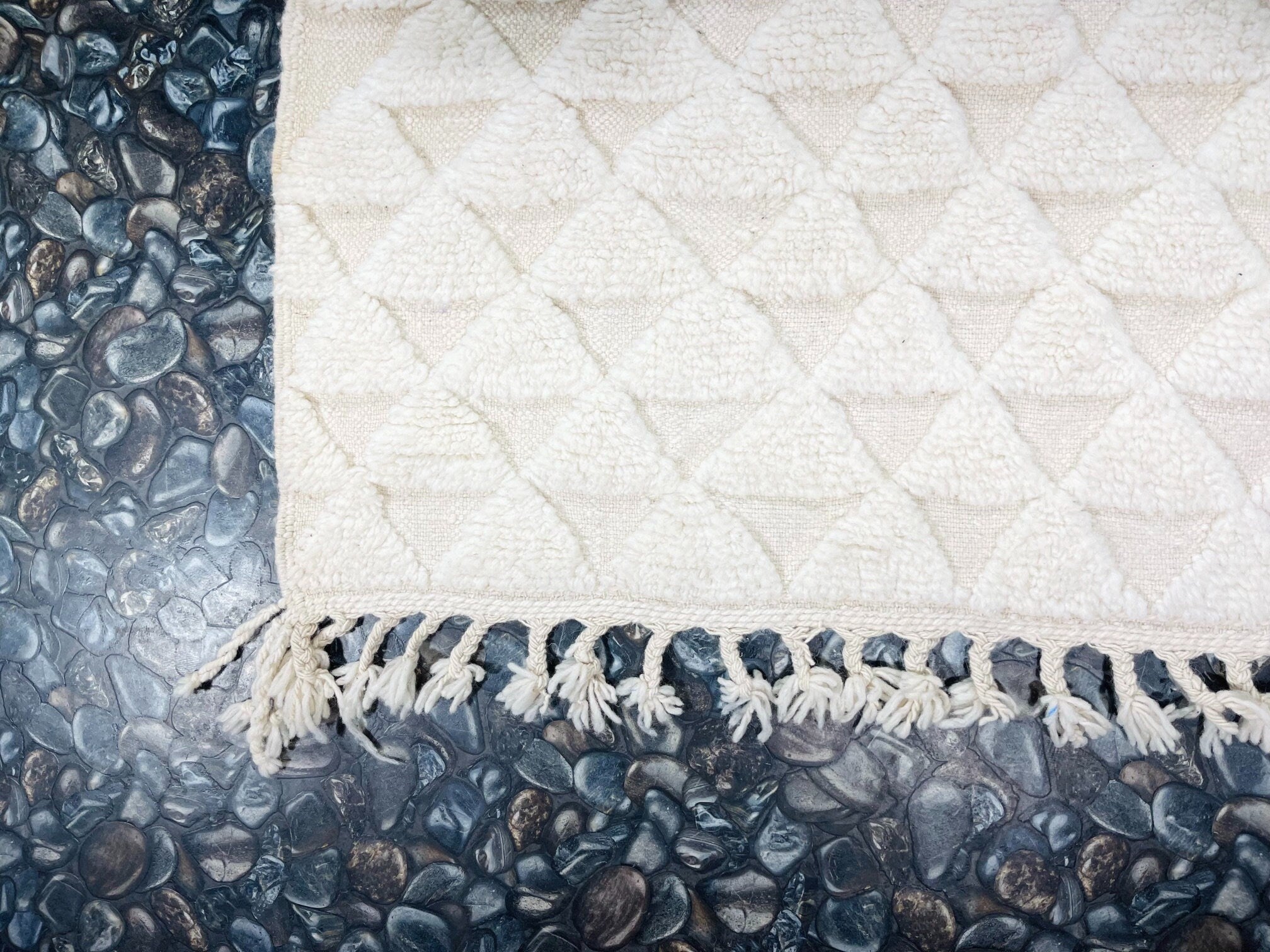 cream textured rug on smooth pebble surface